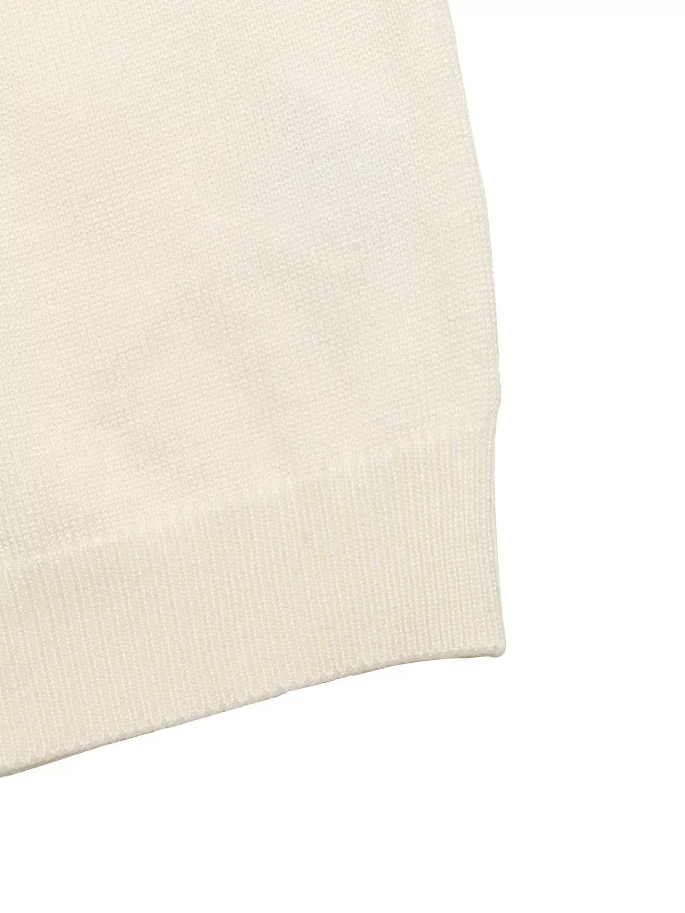 Close up of cream knit top ribbed hem and fine knit texture flat lay