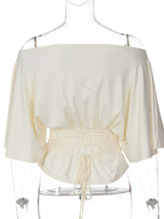 Ivory boat-neck short-sleeve top with ruched waist and adjustable front tie detail.