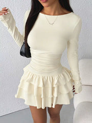 Apricot layered ruffle mini dress worn in a three quarter front view with a black shoulder bag