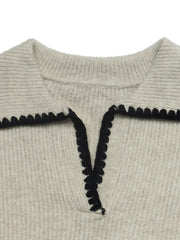 Close up of a cream sweater collar with black scalloped trim and V neckline