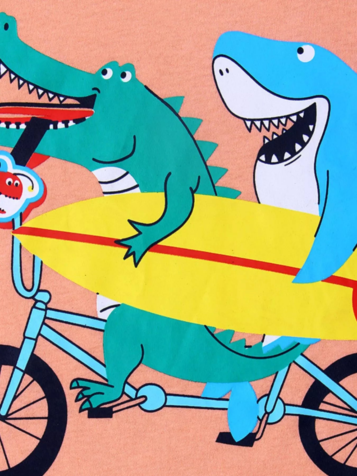 Close up of the crocodile and shark graphic carrying a yellow surfboard on a bicycle