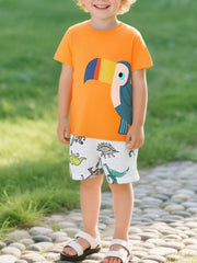On-model front view of orange children's round neck tee with large colorful toucan graphic