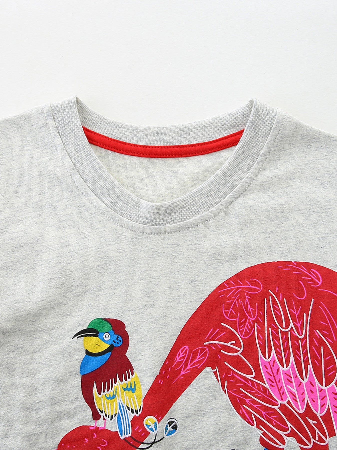 Close-up of light gray crew neckline with red trim and colorful bird print below