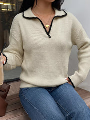 Seated front view of a cream sweater with black scalloped collar trim and V neck