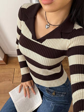 Angled front view of a coffee brown and cream striped ribbed sweater with a V collar