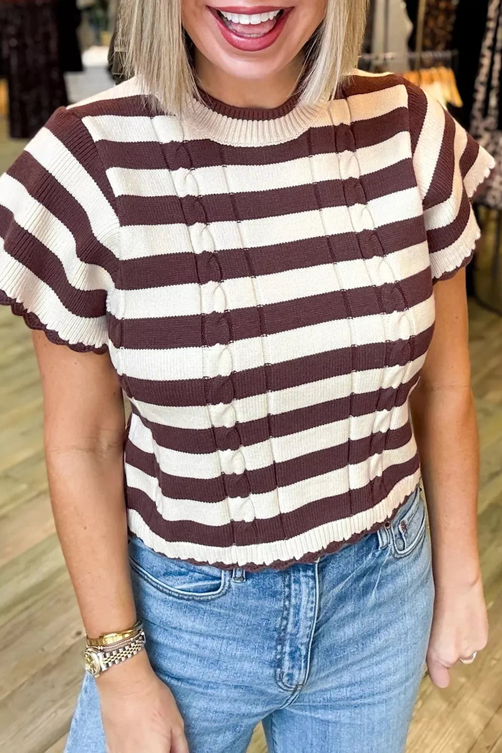 Front view of brown and cream striped ribbed knit sweater with scalloped short sleeves worn indoors.