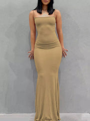 Front view of a camel spaghetti strap bodycon maxi dress worn against a plain gray wall