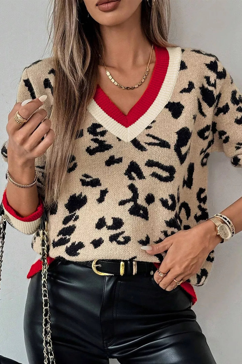 Front view of beige leopard knit sweater with contrast red and cream ribbed cuffs.