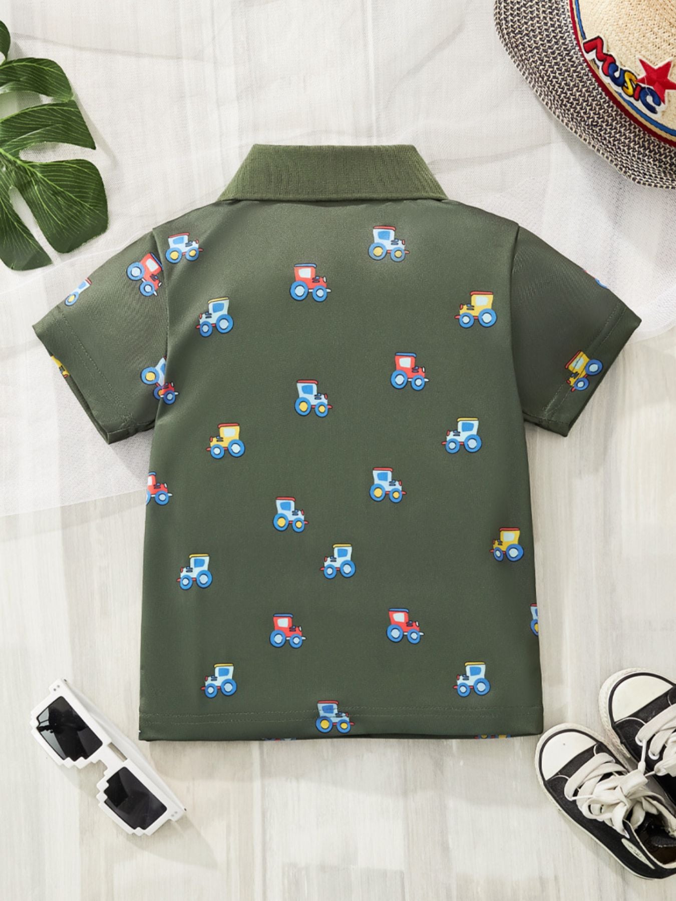 Back view of army green children's polo shirt with small colourful tractor prints laid flat