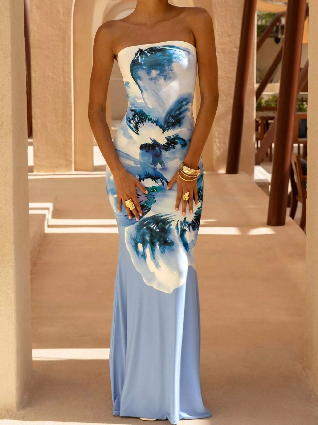 Model wearing strapless light blue and white floral tube maxi dress, front view with hands on thighs