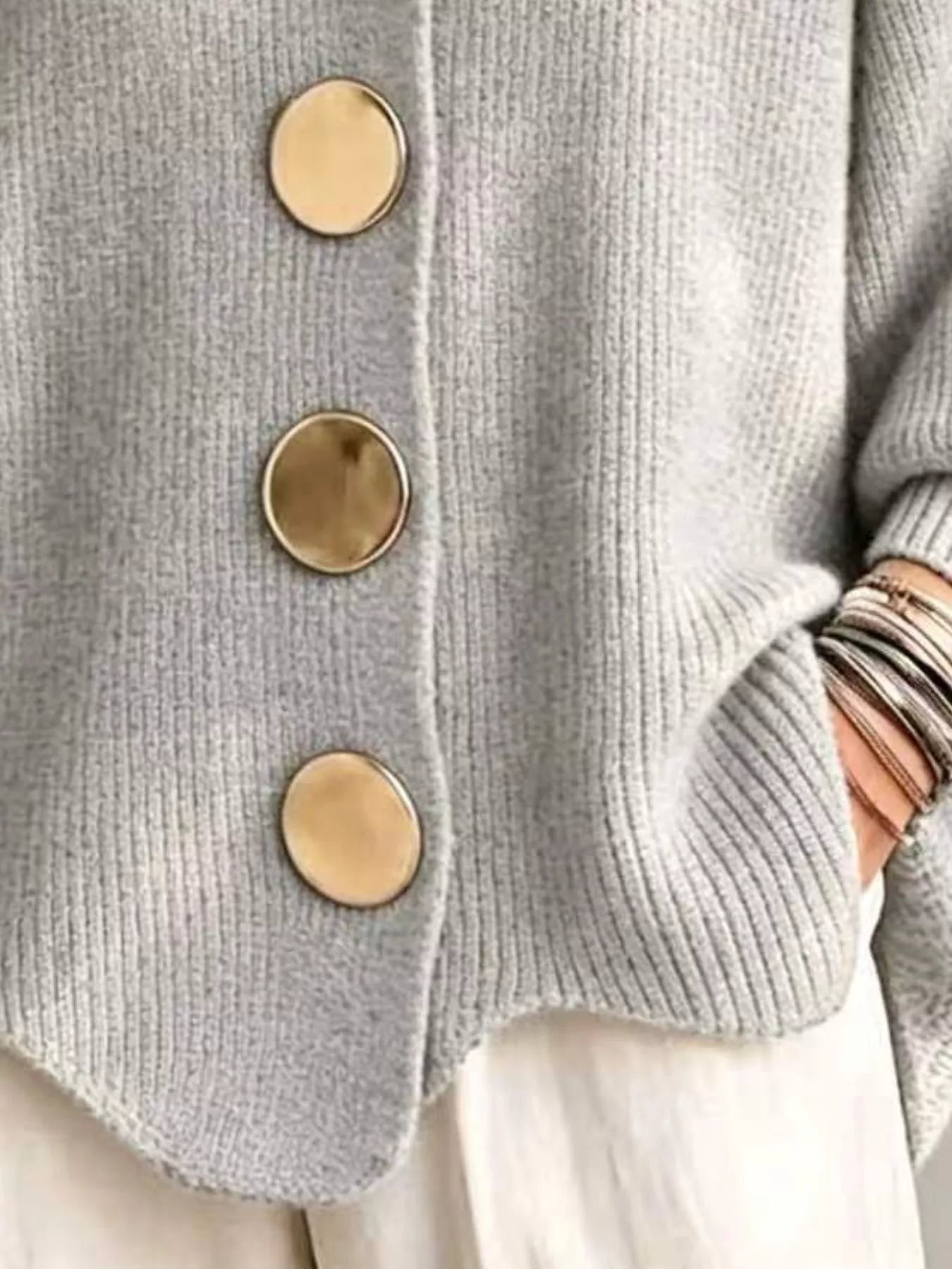Close up of the light gray cardigan gold buttons and scalloped hem