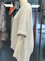 Side view of a white waffle knit cover-up with a long asymmetrical hem on a mannequin
