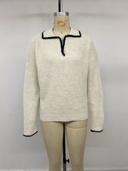 Front view on a mannequin of a cream ribbed sweater with black scalloped collar trim