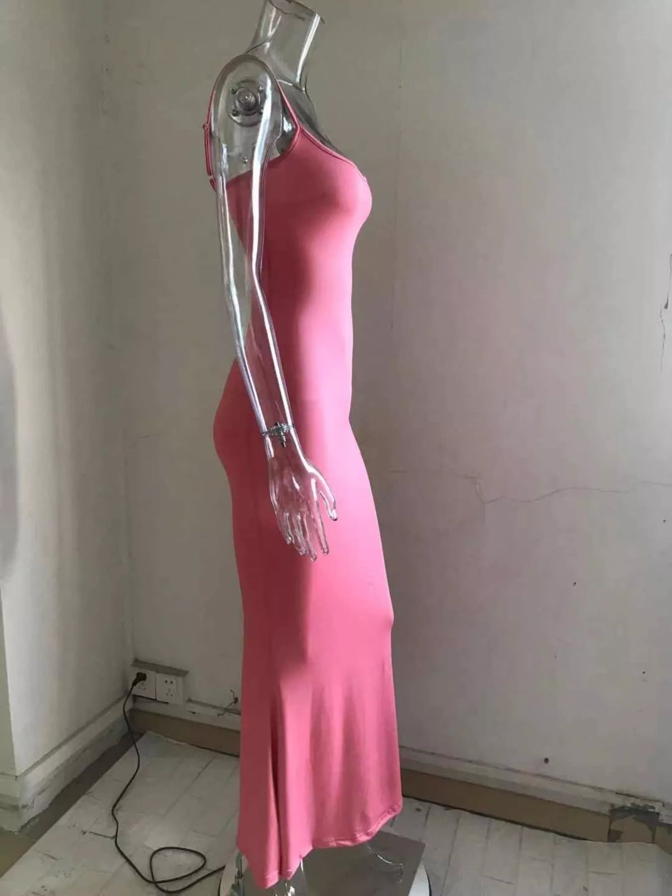 Side view of a burnt coral spaghetti strap bodycon maxi dress on a clear mannequin with a flared hem