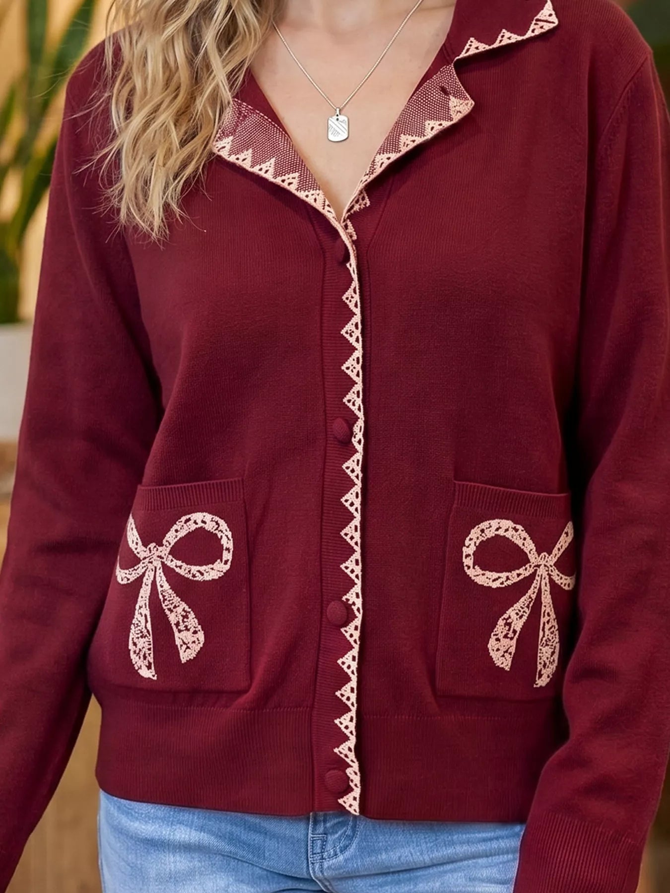 Close front view of the burgundy cardigan collar lace trim and bow pockets