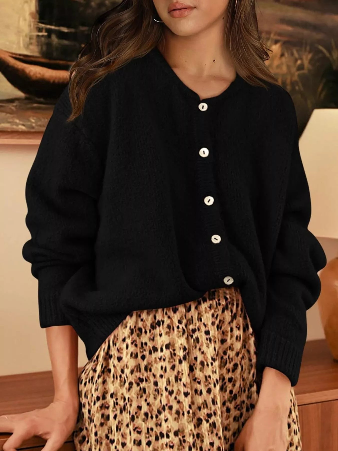Front view of black button down cardigan with white buttons paired with a leopard print skirt