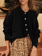 Front view of black button down cardigan with white buttons paired with a leopard print skirt