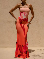 Model standing with hands on hips in strapless coral floral tube maxi dress, front view
