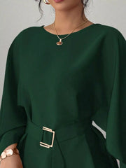 Close view of dark green round neck blouse showing neckline and gold buckle belt