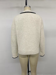 Back view on a mannequin of a plain cream ribbed sweater with black trimmed cuffs