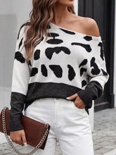 Front view of black and white spotted one shoulder sweater with black hem and white pants