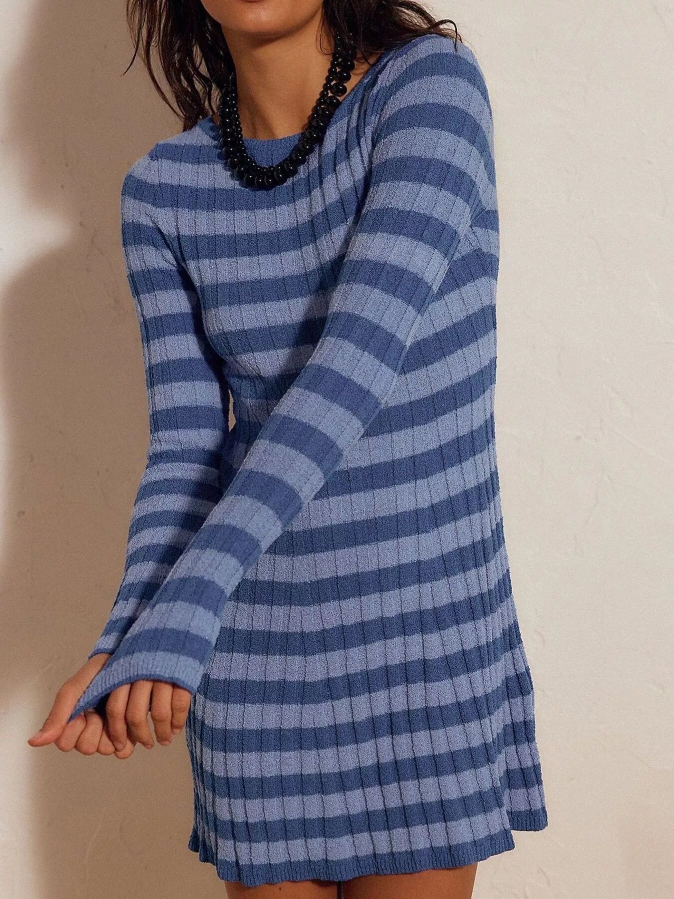 Blue striped ribbed knit long sleeve sweater dress in a front view against a wall