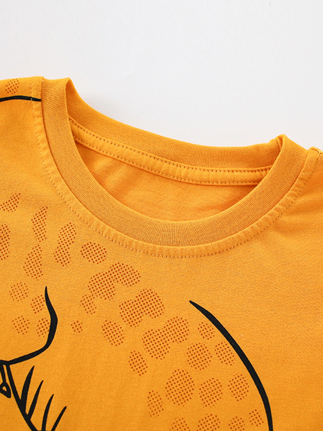 Close-up of the tangerine children's t-shirt neckline and dotted alligator print texture