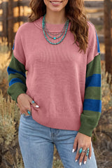 Outdoor front view of the dusty pink sweater with green and blue striped sleeves