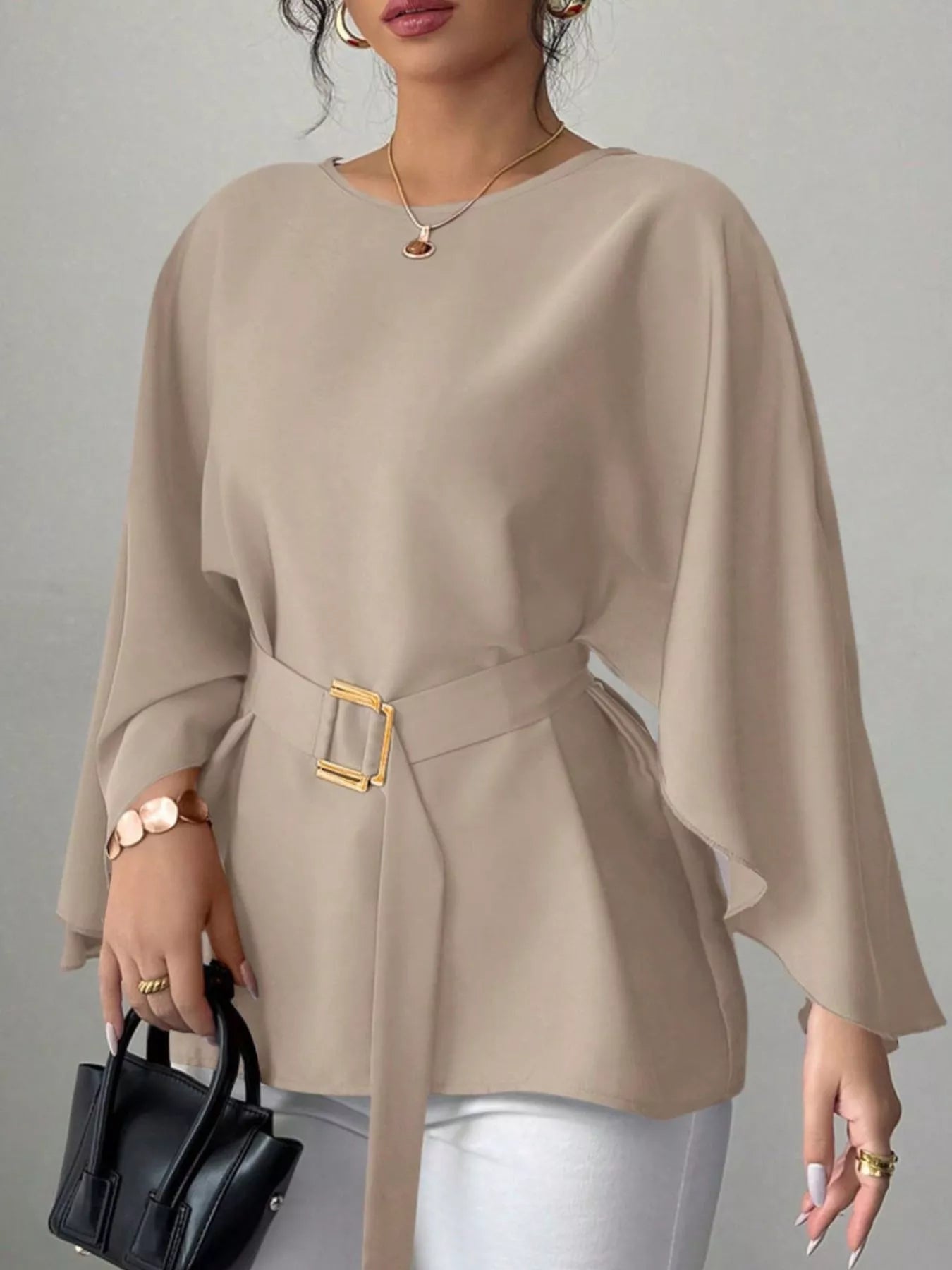 Khaki round neck blouse front view holding black handbag with gold buckle belt