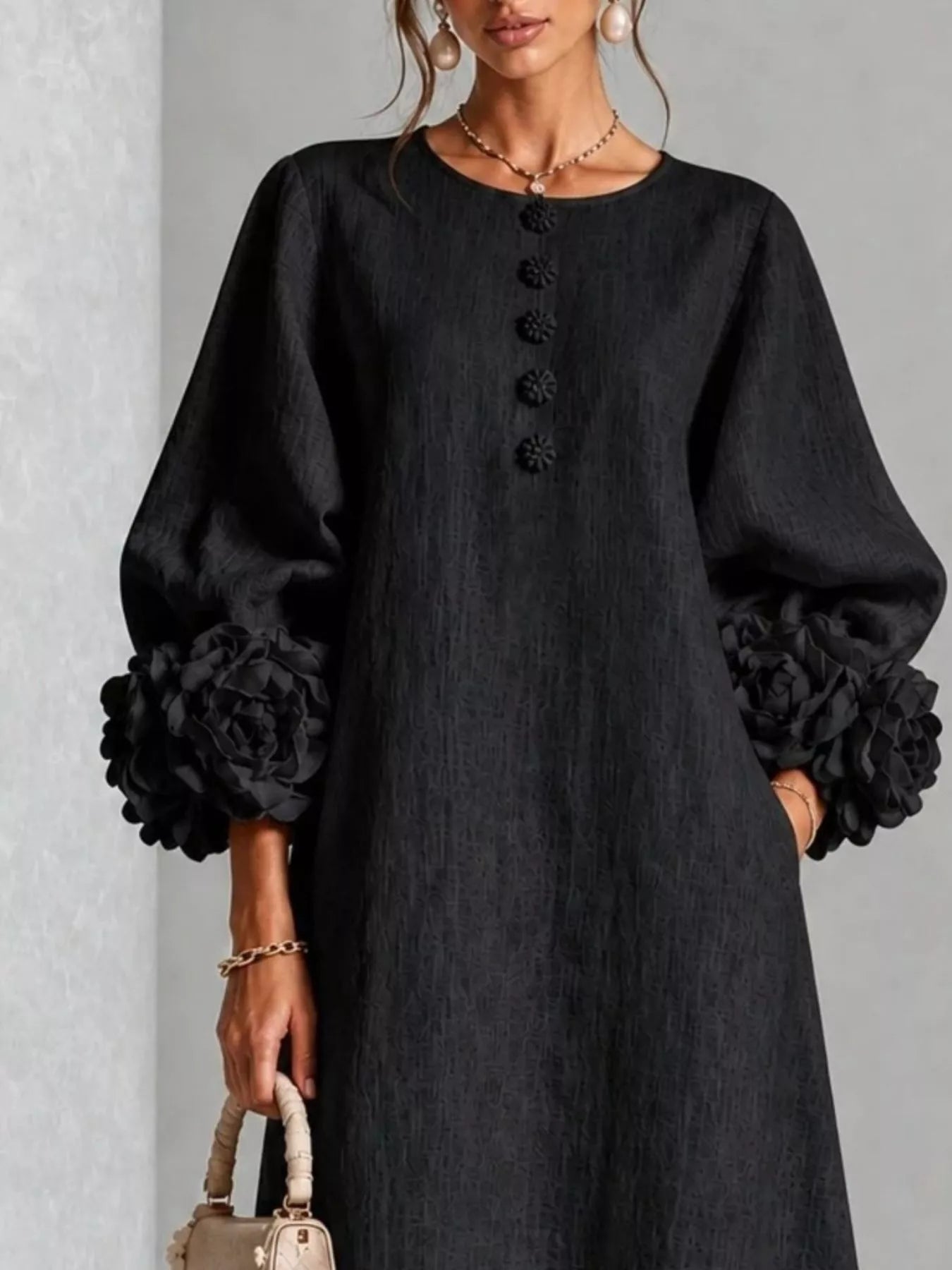 Close front view of the black round neck midi dress bodice with small floral buttons and floral cuffs