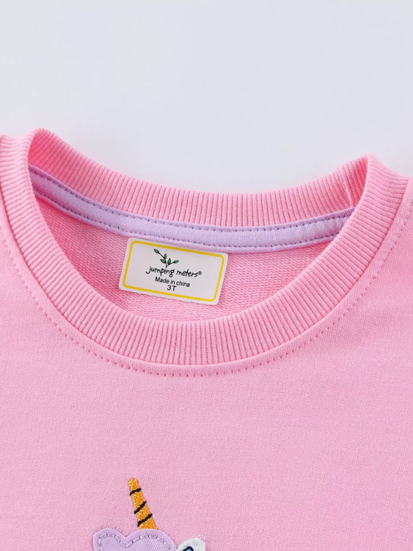 Close view of the ribbed crew neckline on a pink children's sweatshirt