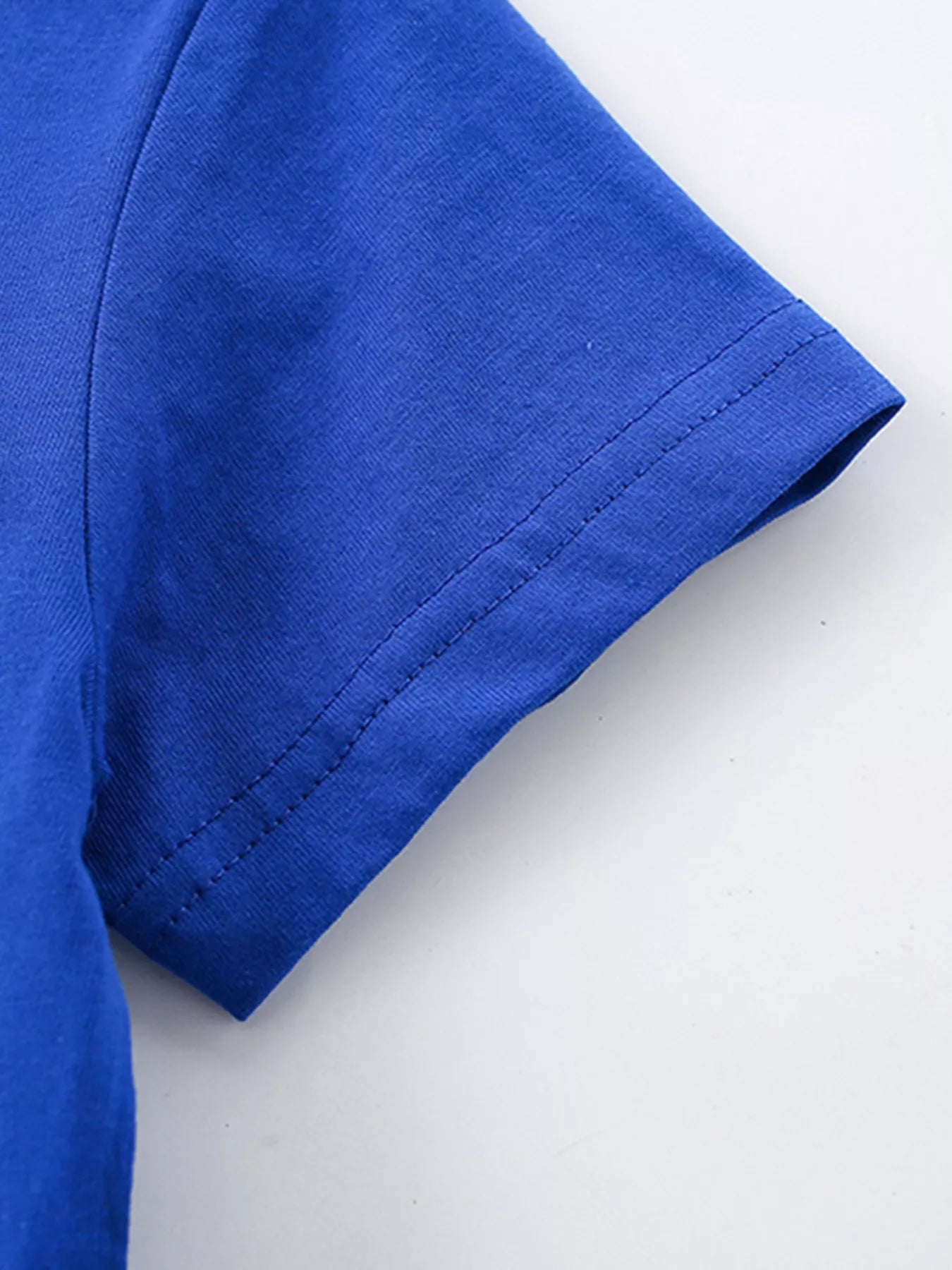 Close-up of royal blue children's short sleeve hem with neat double stitching