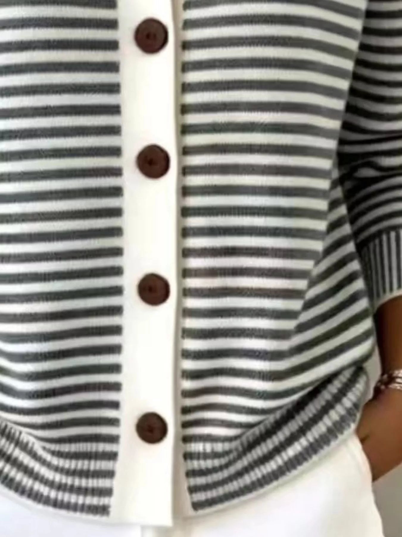 Close-up of the lower front and ribbed hem of a black and white striped knit cardigan