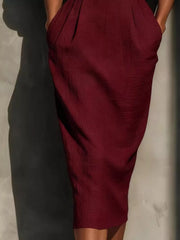 Close view of burgundy puff sleeve midi dress skirt with pleats and waistband
