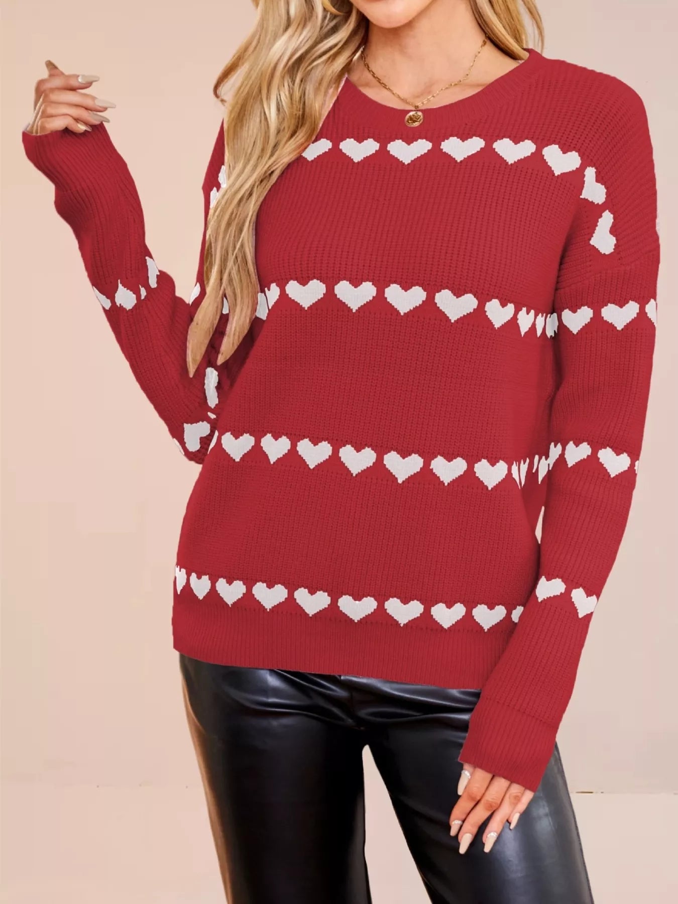 On-model front view of a red dropped shoulder sweater with rows of white hearts