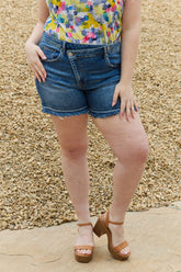Women's mid-rise shorts with off-center buttons, raw hems, and a loose fit.