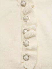 Close up of cream knit top ruffle placket with pearl and crystal buttons detail