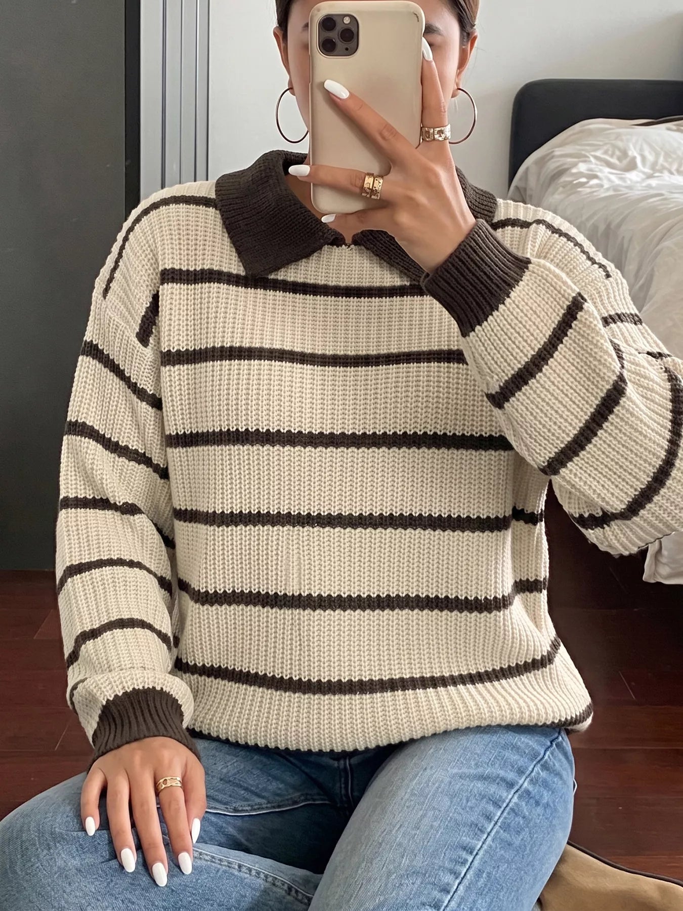 Seated front mirror view of a cream and brown striped knit polo sweater.