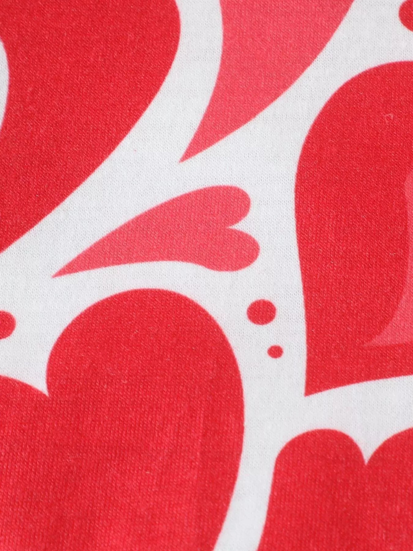 Close view of large red hearts and dots printed on white fabric of children's polo shirt