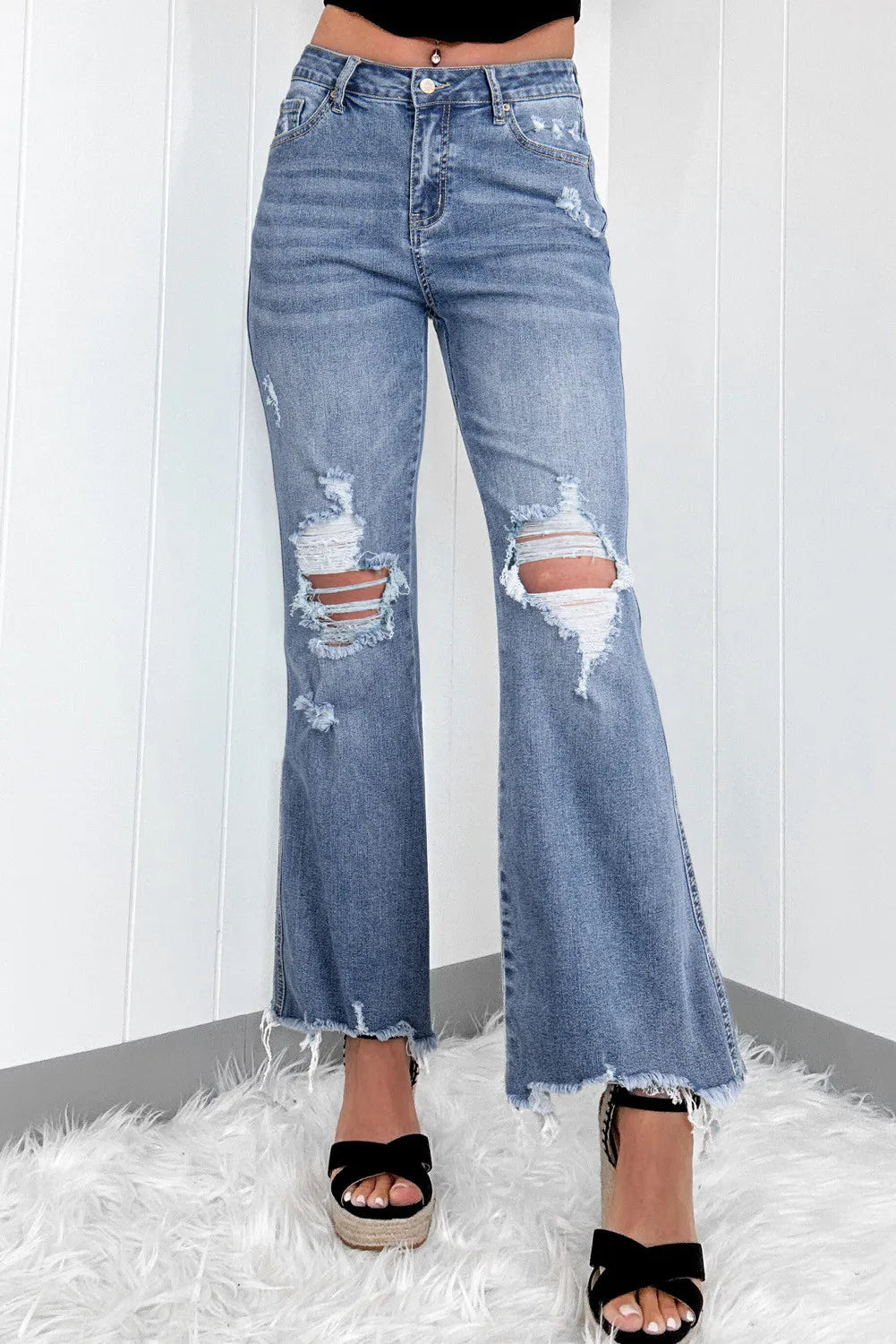 Women's distressed bootcut jeans with raw hems and slightly stretchy fabric.
