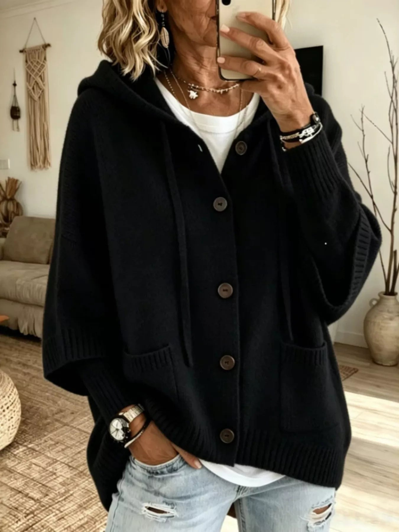 Black hooded knit cardigan with brown buttons and patch pockets shown from the front on model
