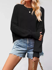 Front view of a black crew neck dropped shoulder sweater with ribbed cuffs worn with denim shorts.