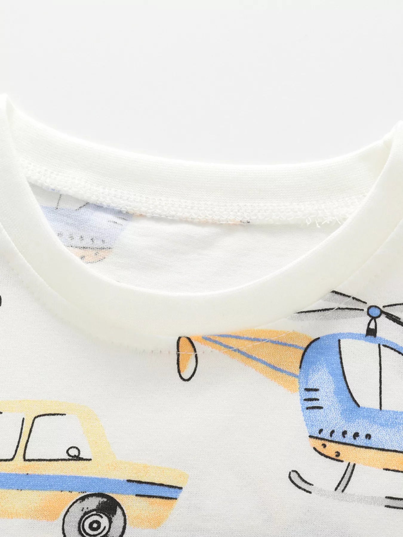 Close-up of the white children's t-shirt neckline with a helicopter and car print