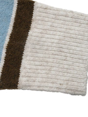 Close up of cream ribbed cuff on blue and brown striped knit sleeve.
