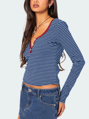 Three quarter side view of blue and navy striped long sleeve t shirt with deep red V neckline trim