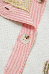 Close-up of the pink ribbed button placket and button on the cream sweater vest