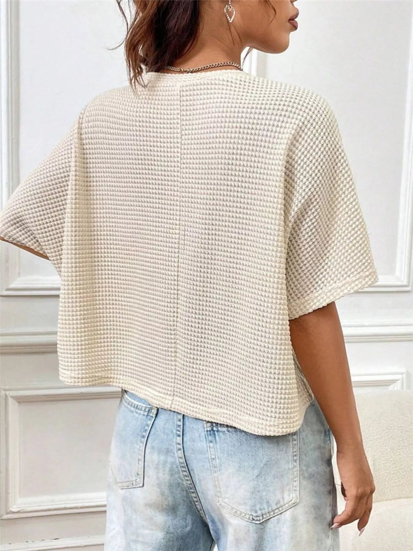 Back view of a cream waffle-knit cropped T-shirt with short sleeves and relaxed fit