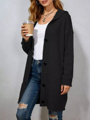 Long black hooded knit cardigan with black buttons worn open over jeans