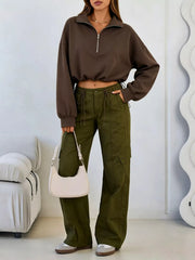 Full length front view of brown half zip sweatshirt with hand in pocket and olive cargo trousers