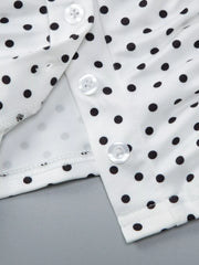 Close-up detail of white polka dot top showing V-neck, ruched fabric, buttons, and cuff.